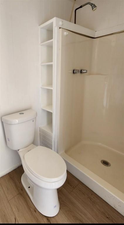 full bath featuring a stall shower, wood finished floors, toilet, and baseboards