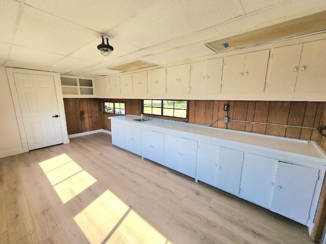 1011 N State Highway 95 N, Bastrop, TX 78602 - kitchen featuring light wood-type flooring, wooden walls, a sink, white cabinets, and baseboards