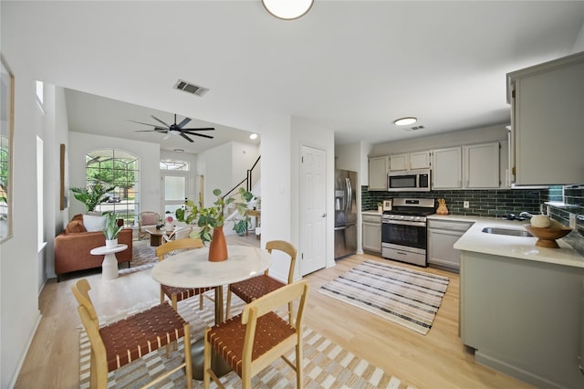 605 Swanson Cv, Austin, TX 78748 - kitchen with stainless steel appliances, light wood-style flooring, gray cabinets, backsplash, and light countertops