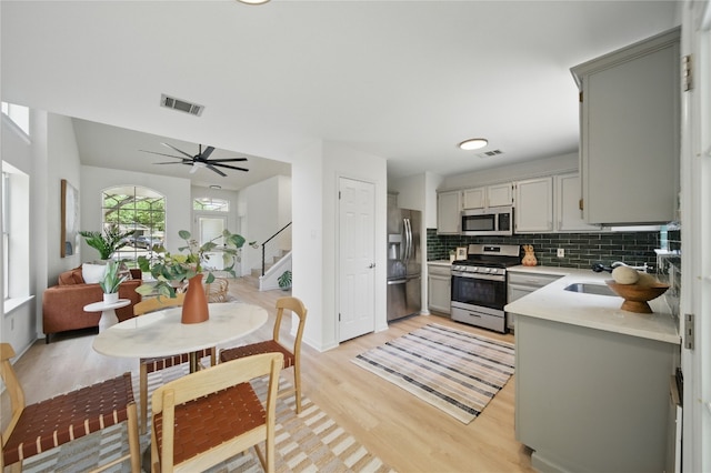 605 Swanson Cv, Austin, TX 78748 - kitchen with appliances with stainless steel finishes, light countertops, light wood-style floors, tasteful backsplash, and gray cabinetry