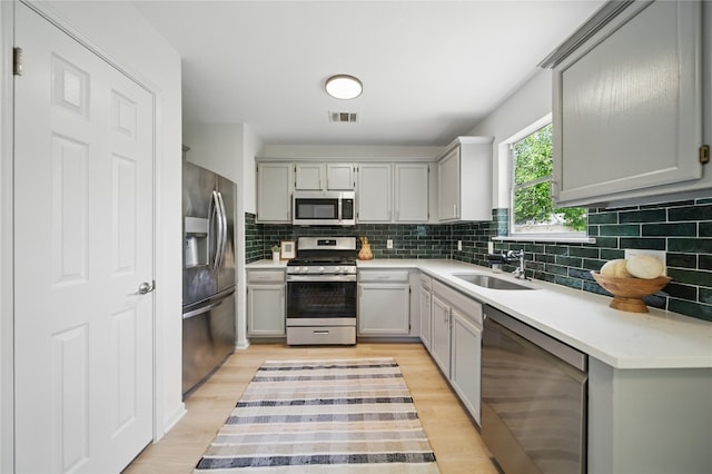 605 Swanson Cv, Austin, TX 78748 - kitchen with appliances with stainless steel finishes, gray cabinets, backsplash, and light wood-style floors