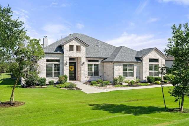 view of front of house featuring stone siding, a chimney, a front lawn, and roof with shingles