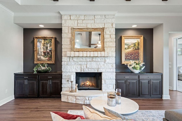 living room with a fireplace, ornamental molding, ceiling fan, dark wood-style flooring, and baseboards