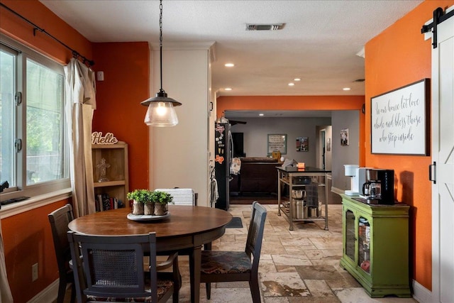 dining area featuring a barn door, stone tile floors, healthy amount of natural light, recessed lighting, and baseboards