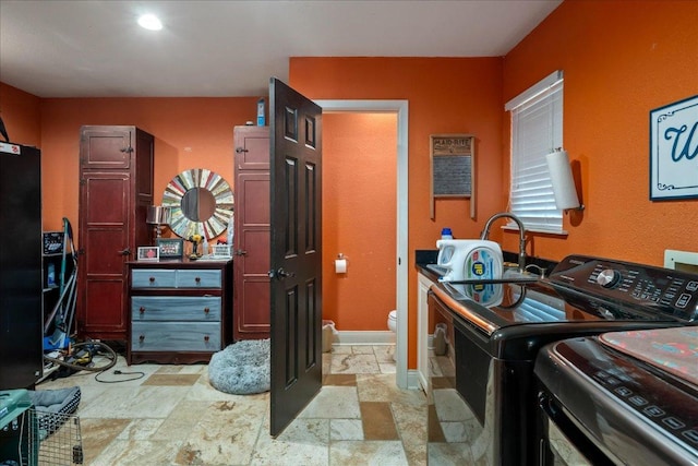 1619 Twin Island Dr, Lockhart, TX 78644 - laundry room featuring stone tile flooring, washing machine and dryer, baseboards, and cabinet space