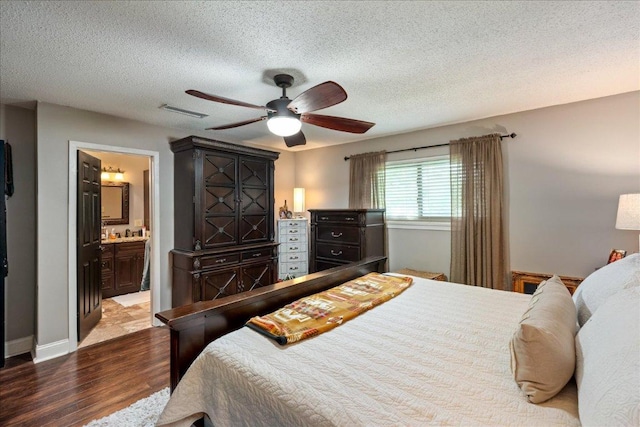 1619 Twin Island Dr, Lockhart, TX 78644 - bedroom featuring wood finished floors, a textured ceiling, ensuite bath, a ceiling fan, and baseboards