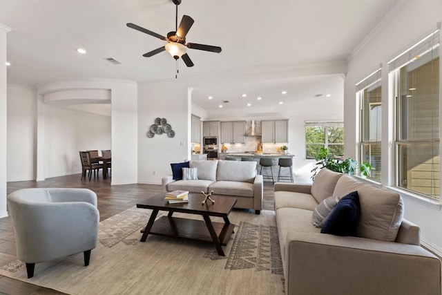 living area with ornamental molding, recessed lighting, light wood finished floors, a ceiling fan, and baseboards