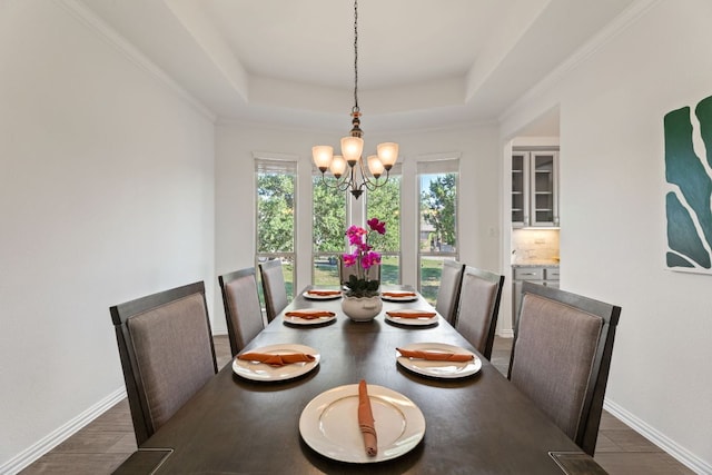 dining space featuring a chandelier, a raised ceiling, and baseboards