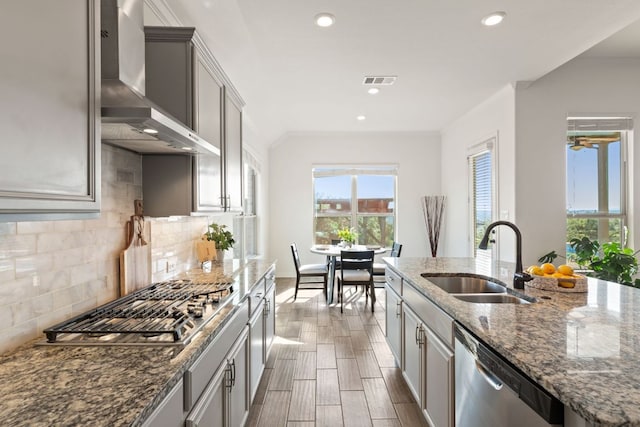 kitchen with wall chimney exhaust hood, a sink, appliances with stainless steel finishes, crown molding, and backsplash