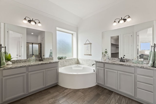 full bathroom with crown molding, a bath, two vanities, wood finished floors, and a shower stall