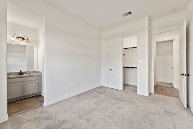 unfurnished bedroom with carpet, a sink, baseboards, and ensuite bath