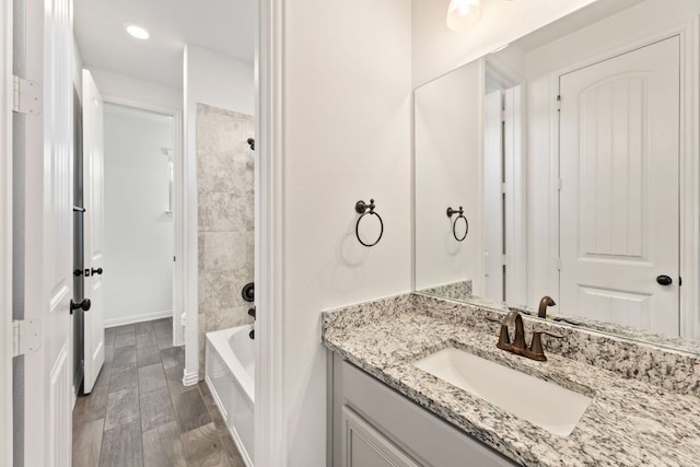 full bath featuring vanity, wood finished floors, tub / shower combination, and baseboards