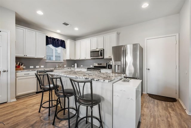651 Bayberry Cir, Buda, TX 78610 - kitchen with appliances with stainless steel finishes, a kitchen island, a kitchen bar, a sink, and backsplash