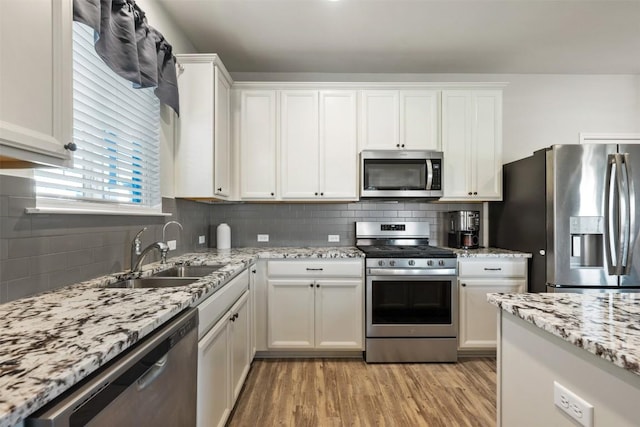 651 Bayberry Cir, Buda, TX 78610 - kitchen with stainless steel appliances, a sink, light wood finished floors, and white cabinetry