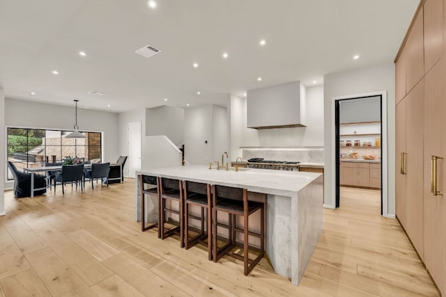 3204 Aztec Fall Cv, Austin, TX 78746 - kitchen featuring modern cabinets, wall chimney exhaust hood, a sink, light countertops, and a large island
