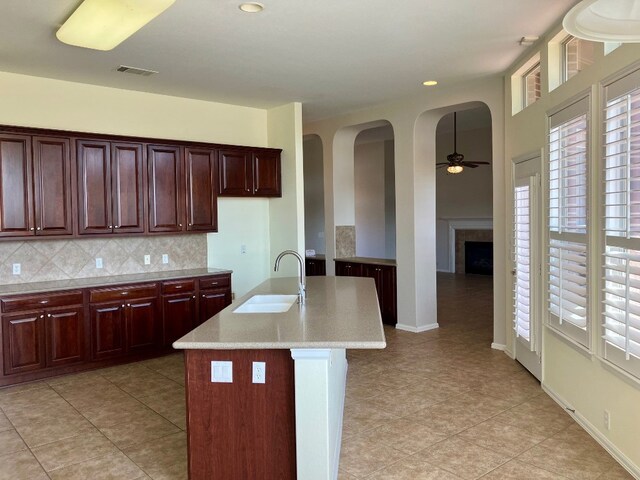 209 Country Creek Dr, Austin, TX 78737 - kitchen featuring a sink, arched walkways, ceiling fan, backsplash, and light tile patterned floors