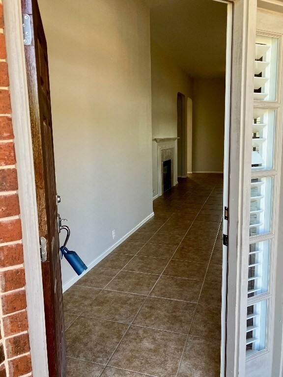 209 Country Creek Dr, Austin, TX 78737 - hallway featuring dark tile patterned floors, arched walkways, and baseboards
