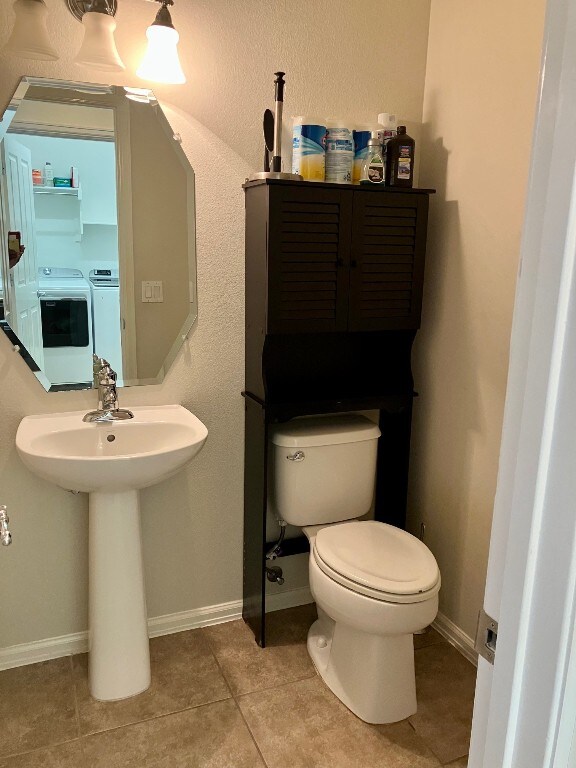 209 Country Creek Dr, Austin, TX 78737 - half bath with toilet, tile patterned flooring, washing machine and clothes dryer, baseboards, and a sink
