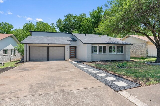 10107 E Rutland Vlg, Austin, TX 78758 - view of front facade featuring a garage, brick siding, concrete driveway, and a front lawn