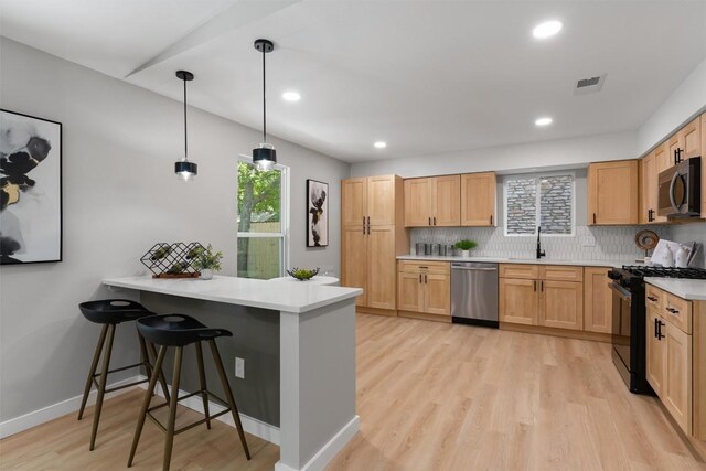 10107 E Rutland Vlg, Austin, TX 78758 - kitchen with stainless steel appliances, a peninsula, light wood-type flooring, decorative backsplash, and recessed lighting