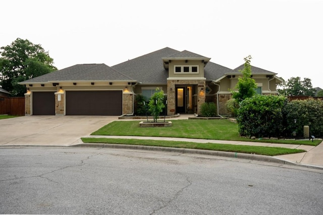 prairie-style house with stone siding, driveway, a garage, and a front yard