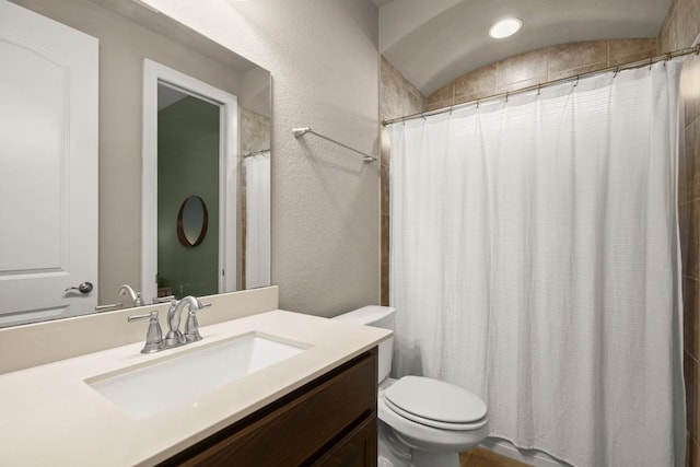 full bath featuring toilet, vanity, a textured wall, and a shower with curtain
