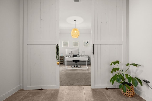 home office with baseboards, light tile patterned flooring, and light colored carpet