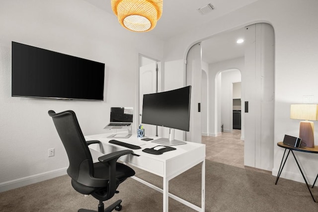 office with arched walkways, baseboards, and carpet flooring