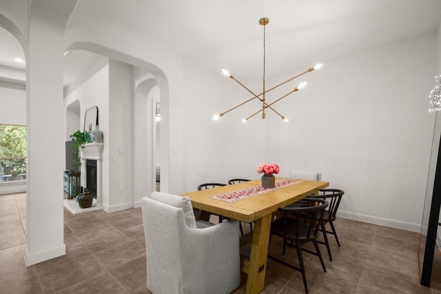 tiled dining room featuring arched walkways, a chandelier, and baseboards