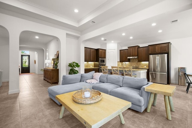 living area with arched walkways, recessed lighting, light tile patterned flooring, baseboards, and ornamental molding