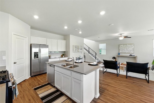 10207 Buster Dr, Austin, TX 78748 - kitchen featuring appliances with stainless steel finishes, a sink, open floor plan, wood finished floors, and white cabinetry