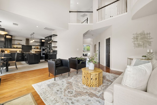 701 Stansted Manor Dr, Pflugerville, TX 78660 - living room featuring arched walkways, light wood finished floors, and a towering ceiling