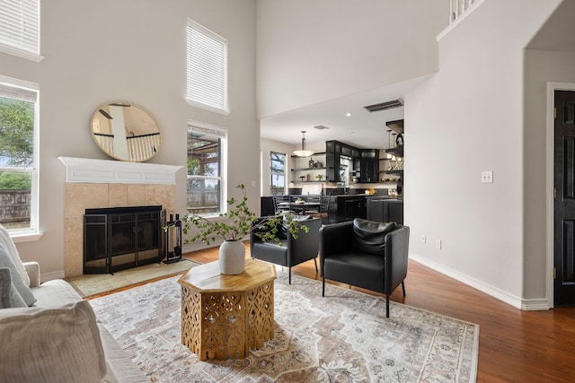 701 Stansted Manor Dr, Pflugerville, TX 78660 - living room with light wood finished floors, a tile fireplace, a towering ceiling, and baseboards
