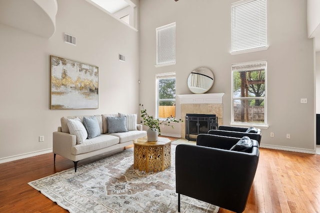 701 Stansted Manor Dr, Pflugerville, TX 78660 - living room with a towering ceiling, a tiled fireplace, light wood-style flooring, and baseboards