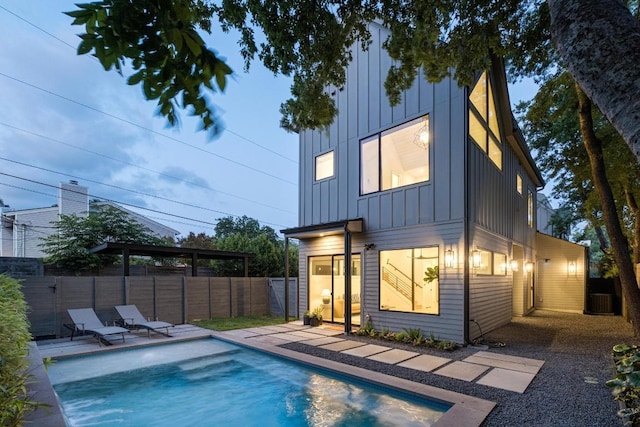 rear view of property with board and batten siding, a fenced backyard, cooling unit, and a patio area