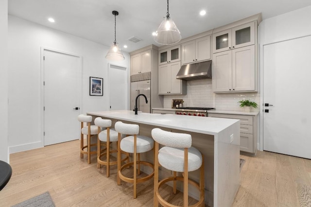 1908 Goodrich Ave Unit B, Austin, TX 78704 - kitchen with under cabinet range hood, stainless steel built in refrigerator, backsplash, a center island with sink, and light countertops