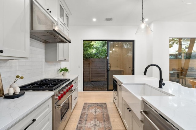 1908 Goodrich Ave Unit B, Austin, TX 78704 - kitchen featuring under cabinet range hood, stainless steel appliances, a sink, decorative backsplash, and white cabinets