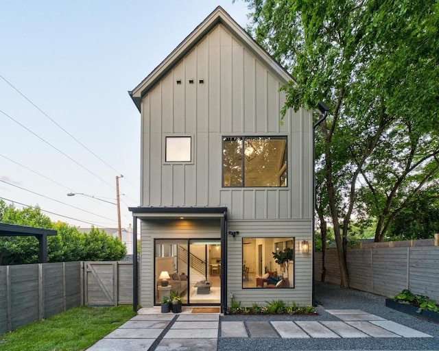 back of house featuring board and batten siding, a fenced backyard, and a gate