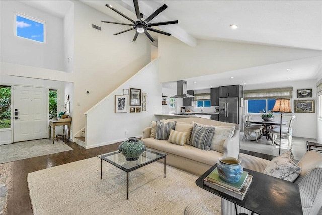 living room with stairway, wood finished floors, high vaulted ceiling, beamed ceiling, and a ceiling fan