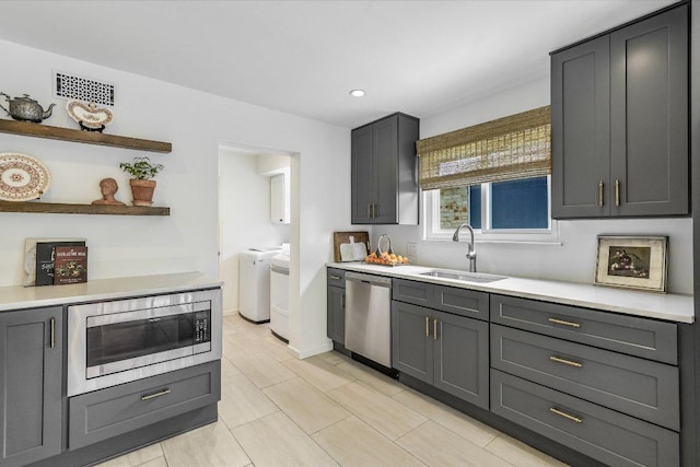 kitchen featuring a sink, washing machine and dryer, appliances with stainless steel finishes, light countertops, and recessed lighting