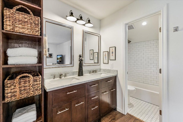 full bath with toilet, double vanity, washtub / shower combination, and wood finished floors