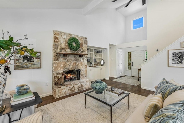 living area featuring wood finished floors, baseboards, a fireplace, beam ceiling, and high vaulted ceiling