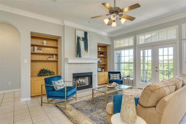 5133 Valburn Ct, Austin, TX 78731 - living area featuring built in shelves, light tile patterned floors, ornamental molding, a tiled fireplace, and a ceiling fan