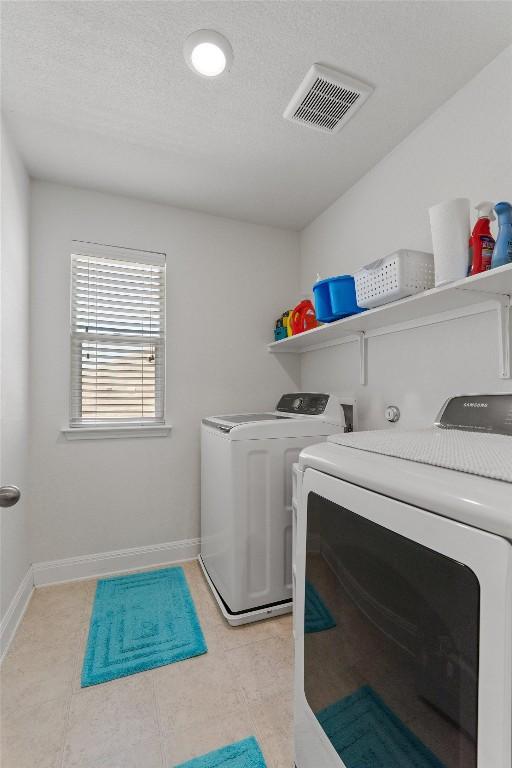 7609 Lazy Creek Dr, Austin, TX 78724 - washroom featuring washing machine and clothes dryer, light tile patterned flooring, and baseboards