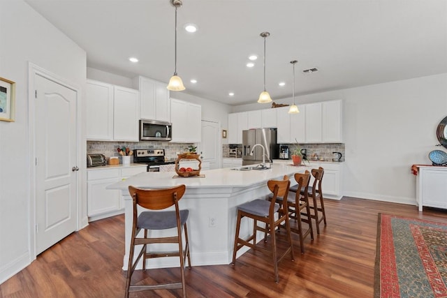 7609 Lazy Creek Dr, Austin, TX 78724 - kitchen featuring appliances with stainless steel finishes, dark wood-style flooring, tasteful backsplash, a breakfast bar, and an island with sink