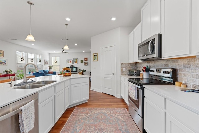 7609 Lazy Creek Dr, Austin, TX 78724 - kitchen featuring stainless steel appliances, light wood finished floors, open floor plan, backsplash, and recessed lighting