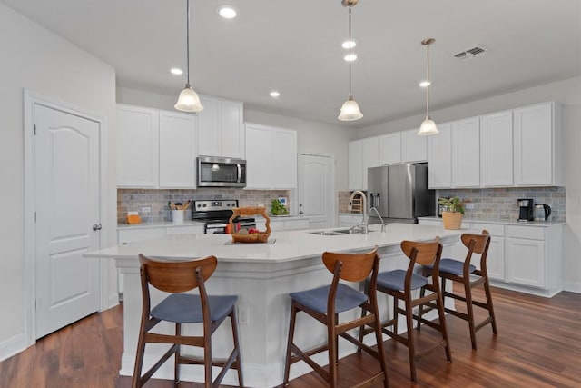 7609 Lazy Creek Dr, Austin, TX 78724 - kitchen with appliances with stainless steel finishes, tasteful backsplash, a center island with sink, light countertops, and a breakfast bar