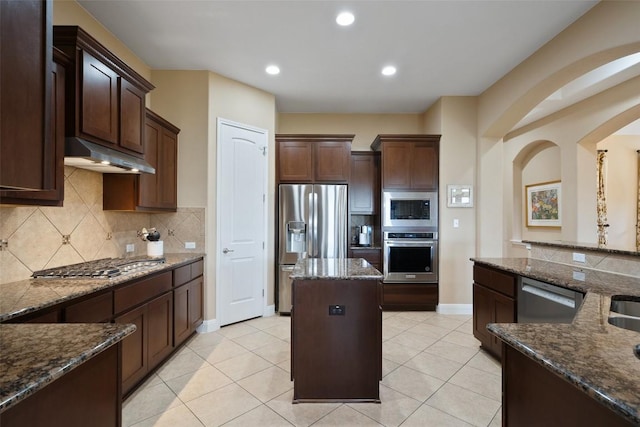 937 Wild Rose Dr, Austin, TX 78737 - kitchen with stainless steel appliances, under cabinet range hood, tasteful backsplash, arched walkways, and dark stone countertops