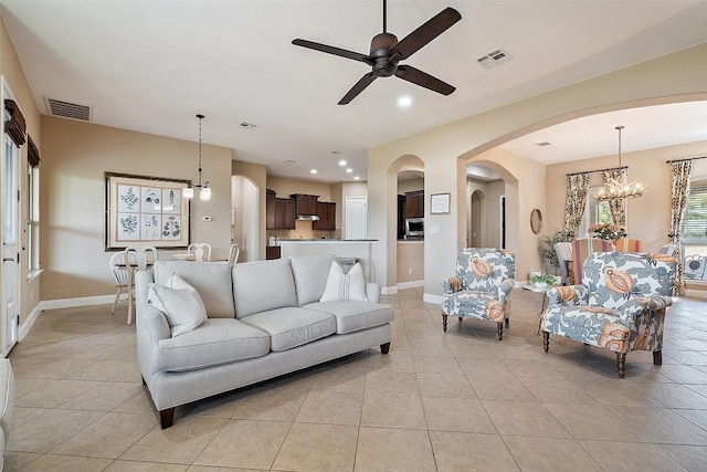 living area with light tile patterned floors, arched walkways, baseboards, a ceiling fan, and recessed lighting