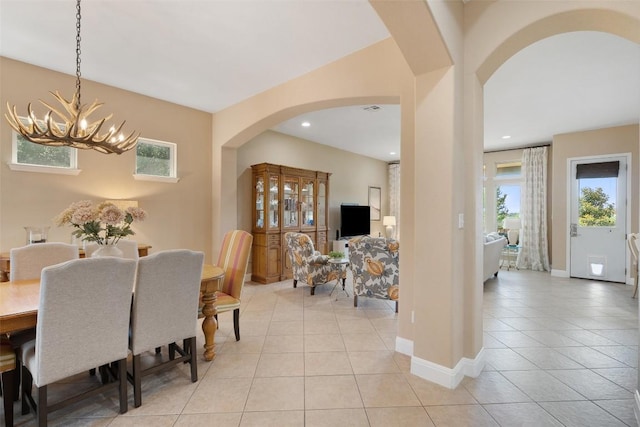 dining area featuring arched walkways, a chandelier, light tile patterned floors, baseboards, and recessed lighting